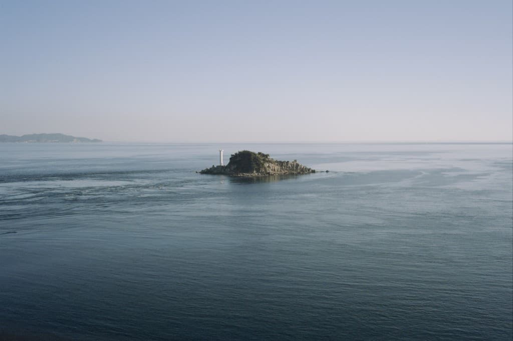 A small island with a lighthouse in the open sea